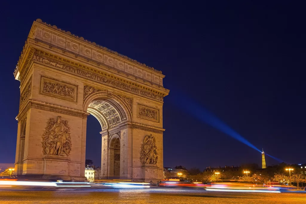 The arc de triomphe at night with cars driving around it