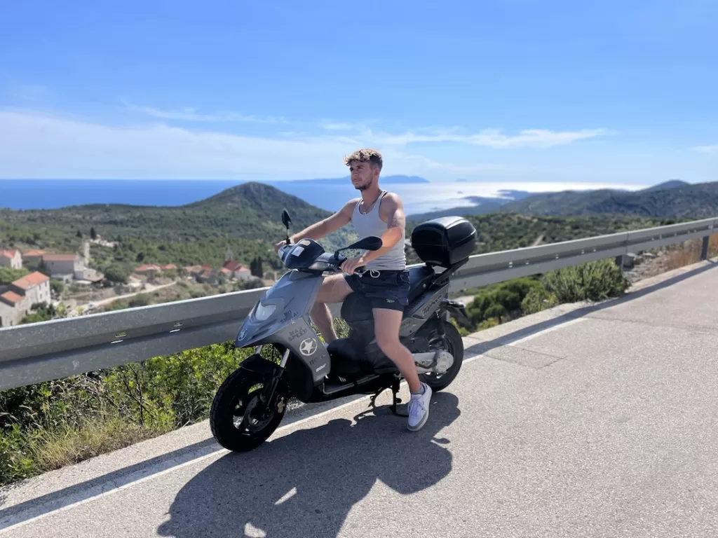 me on a scooter with the mountains of Hvar and Adriatic sea in the background