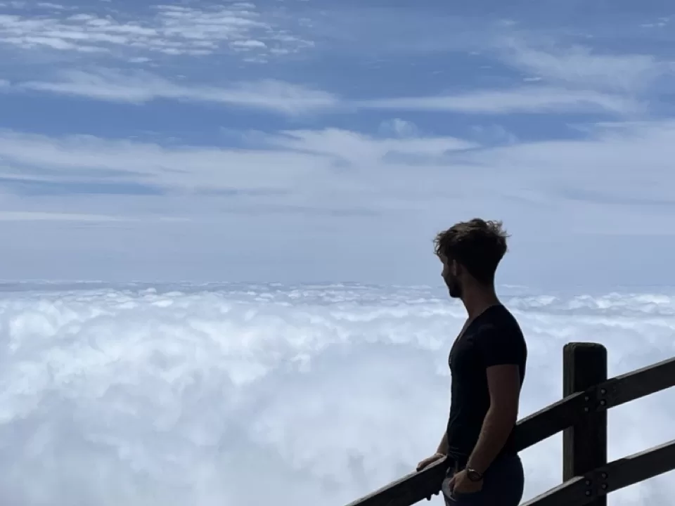 me standing by a fence overlooking a sea of clouds rolling underneath
