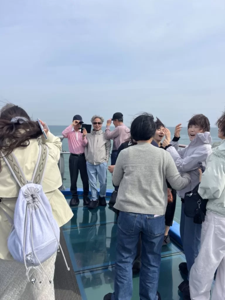 group of tourists walking on a glass walkway out into the sea
