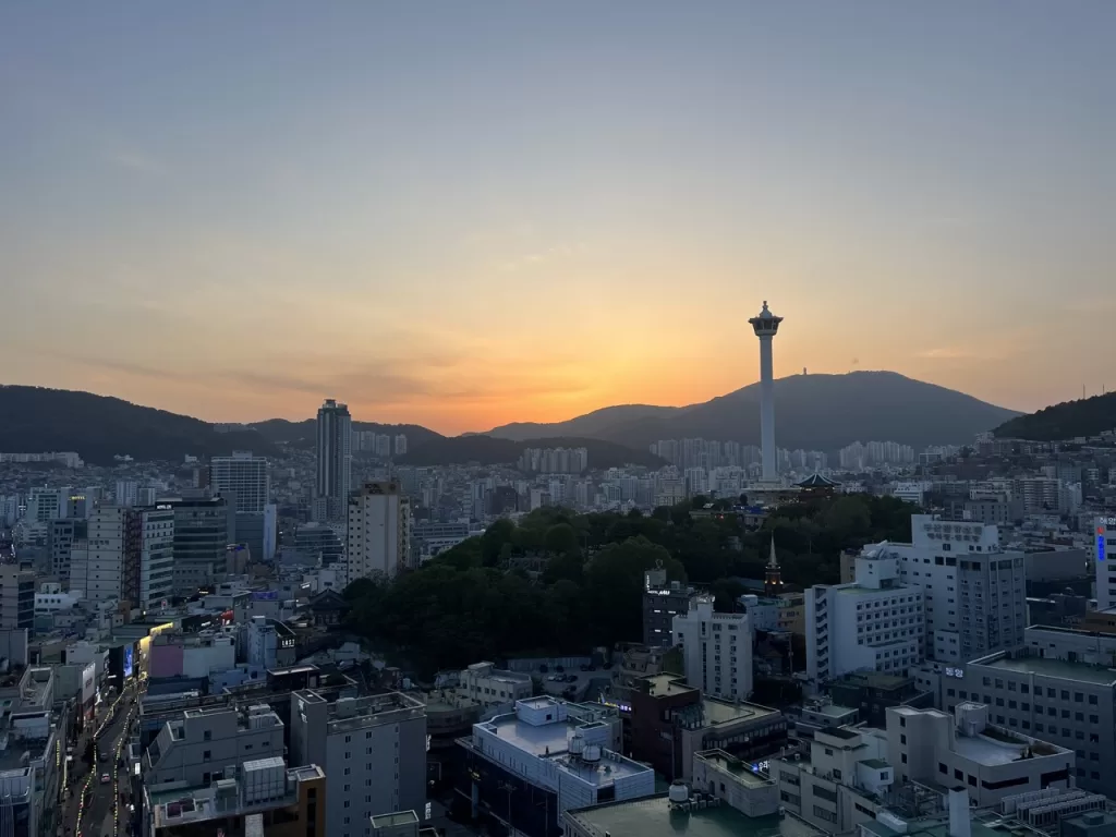 busan skyline with a large tower with the sun setting over the mountains in the background