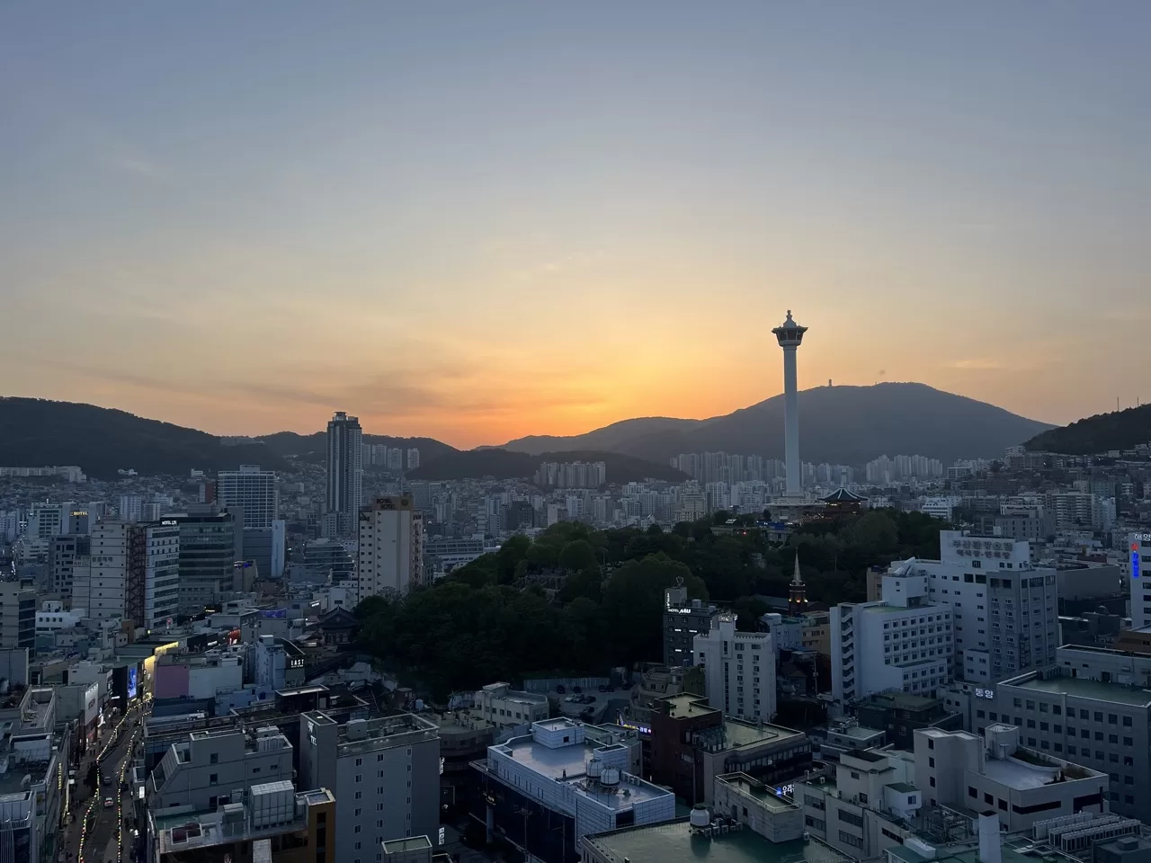 busan skyline with a large tower with the sun setting over the mountains in the background