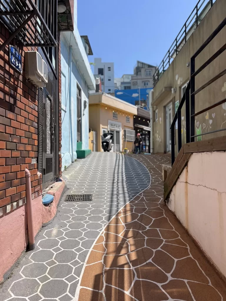 steep, narrow road with hexagonal artistic tiles and small multicolored homes on the side