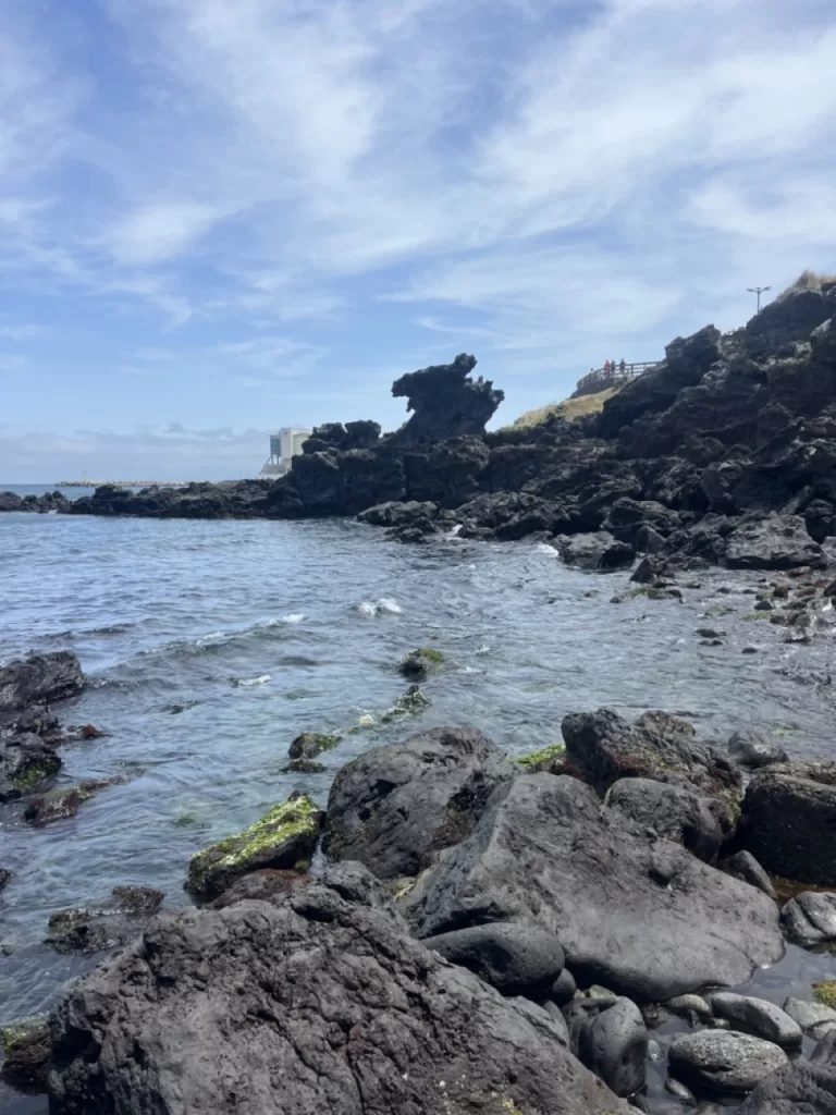 a large natural lava rock shaped like the head of a dragon towering over the coastline